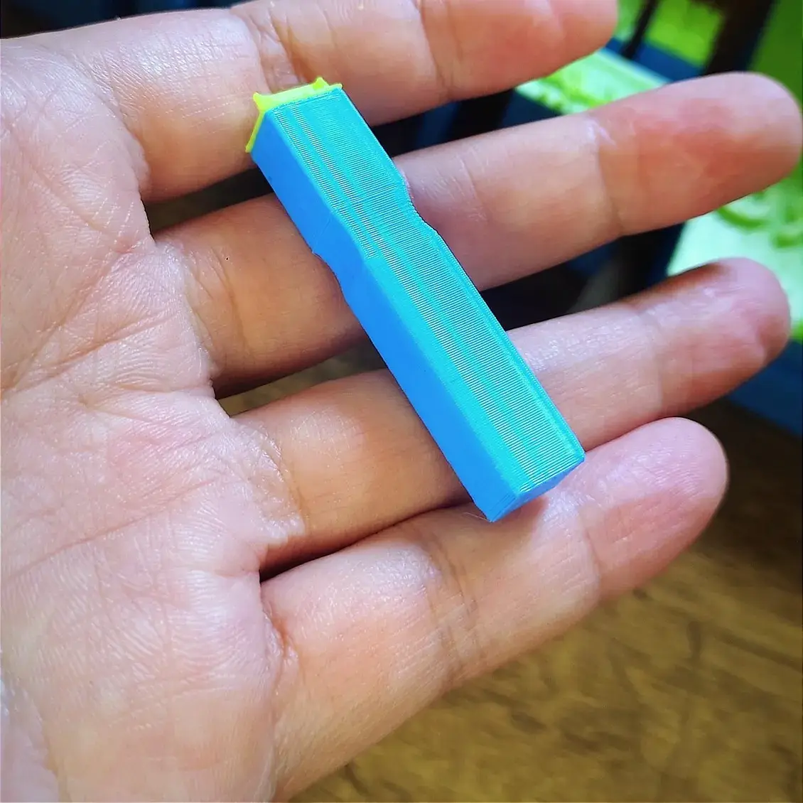 Carimbo personalizado de bloco pequeno, azul com face verde, na palma da mão